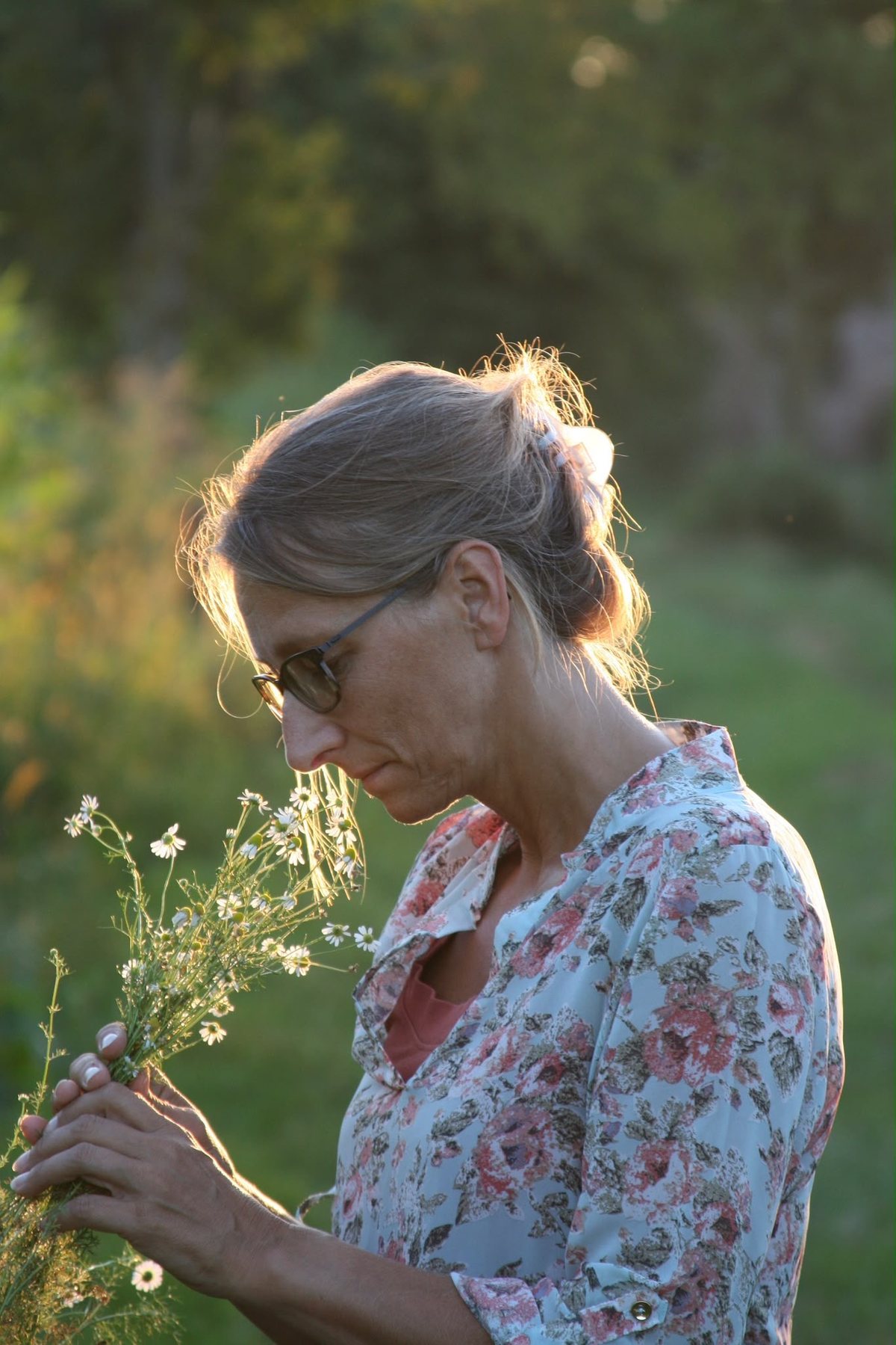 Anja Hoffmann betrachtet kleine Wiesenblüten im warmen Abendlicht
